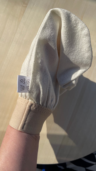 : Raw silk exfoliating glove for body peeling, displayed on a neutral background with clean, minimalist design.