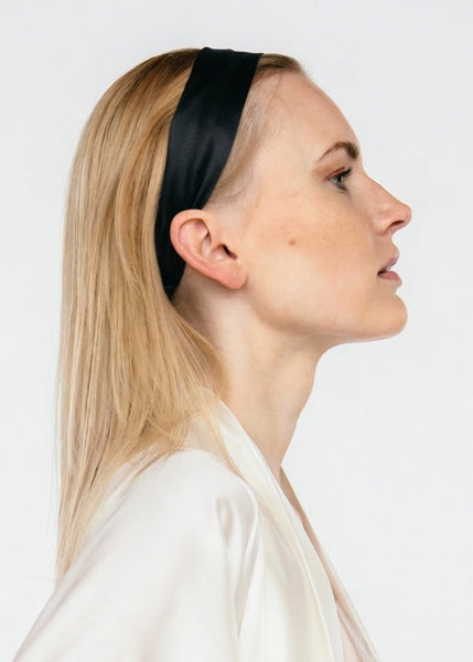 A side-profile portrait of a blonde woman wearing a wide, solid black silk  headband and a light cream silk obe